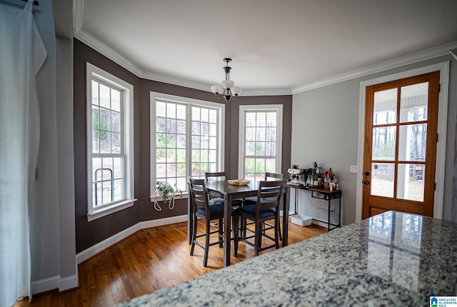 dining area with wood-type flooring, an inviting chandelier, and crown molding