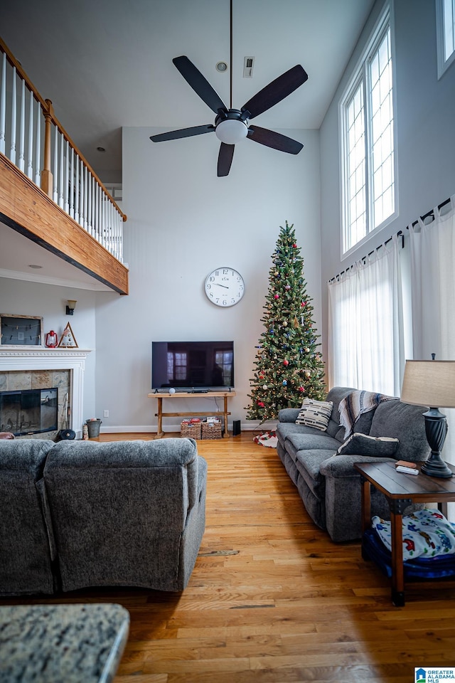 living area featuring a high ceiling, wood finished floors, visible vents, and a tile fireplace