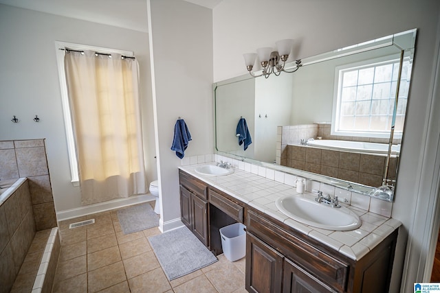 bathroom with an inviting chandelier, tile patterned floors, tiled bath, toilet, and vanity