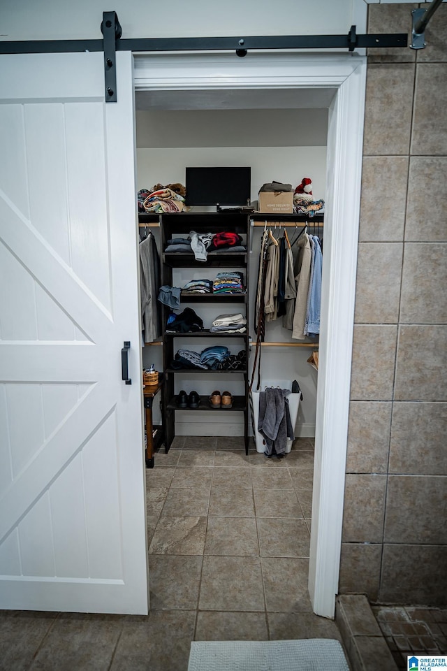 spacious closet featuring a barn door and tile patterned floors