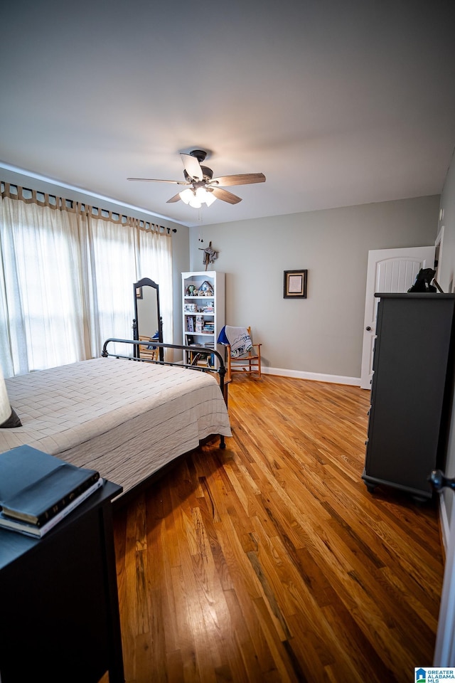 bedroom with ceiling fan, baseboards, and wood finished floors