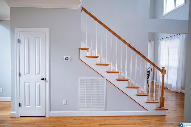 staircase with hardwood / wood-style floors and ornamental molding