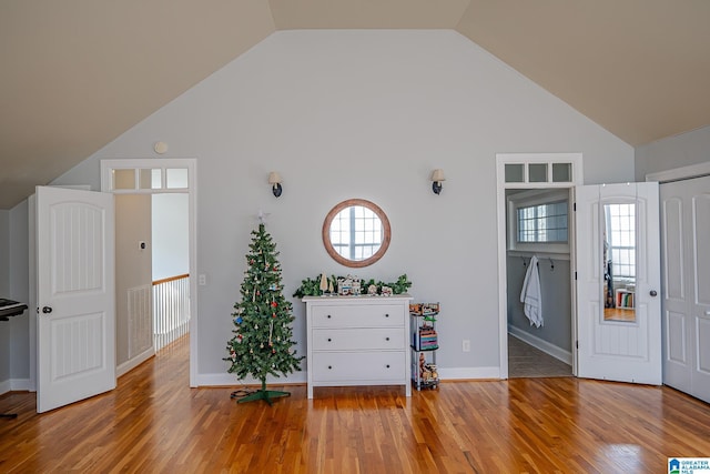 entrance foyer with baseboards, light wood-style floors, a healthy amount of sunlight, and high vaulted ceiling