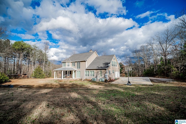 rear view of house with a patio, a lawn, and a chimney