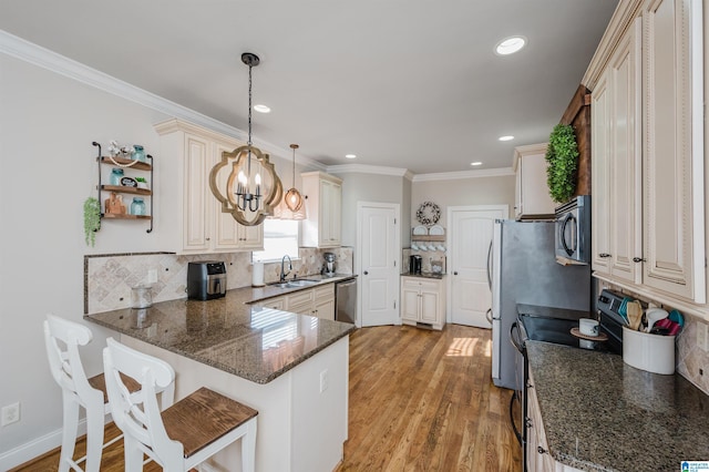 kitchen with decorative backsplash, stainless steel appliances, kitchen peninsula, and hanging light fixtures