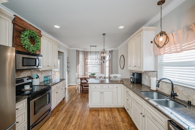 kitchen with pendant lighting, sink, kitchen peninsula, and stainless steel appliances