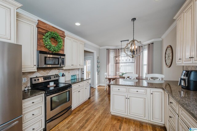 kitchen with a notable chandelier, light hardwood / wood-style floors, decorative light fixtures, appliances with stainless steel finishes, and ornamental molding