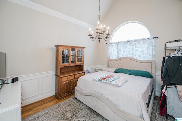 bedroom with vaulted ceiling, an inviting chandelier, light hardwood / wood-style flooring, and ornamental molding