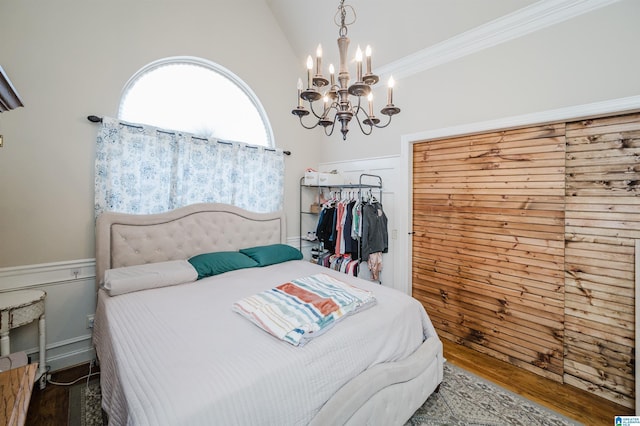 bedroom with wood-type flooring, lofted ceiling, ornamental molding, and an inviting chandelier