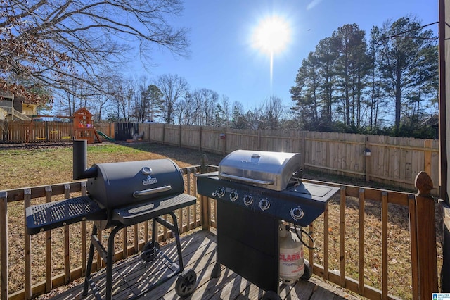 wooden deck with a playground and grilling area