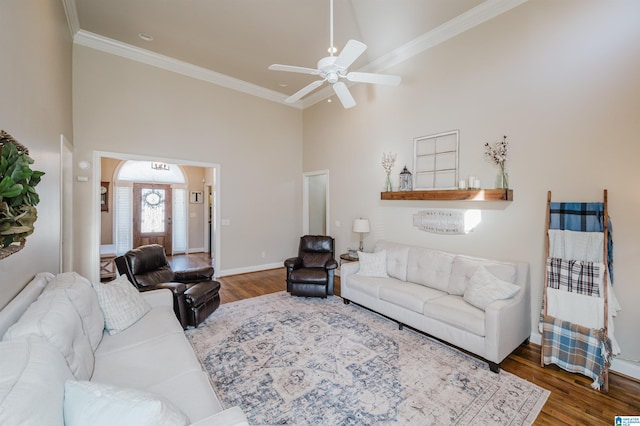 living room with a high ceiling, dark hardwood / wood-style flooring, ceiling fan, and crown molding