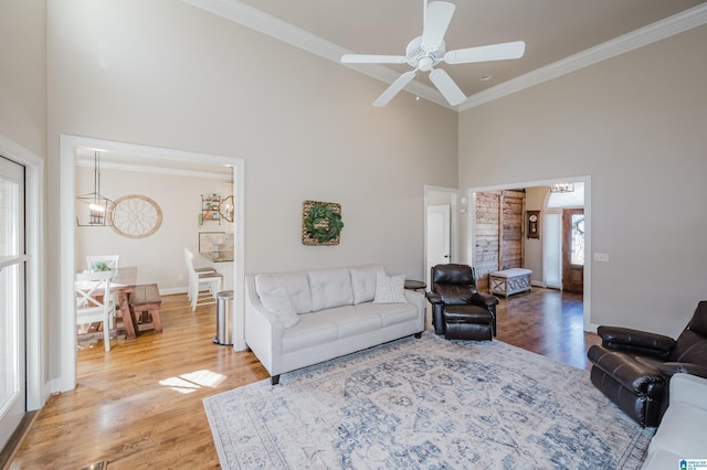 living room featuring hardwood / wood-style floors, a towering ceiling, ceiling fan, and crown molding