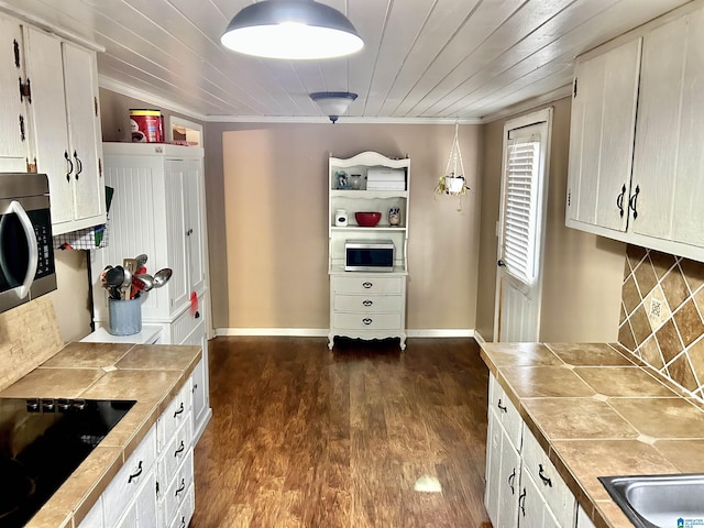 kitchen featuring ornamental molding, black electric cooktop, hanging light fixtures, dark hardwood / wood-style floors, and tile counters