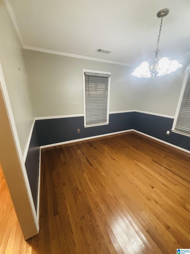 unfurnished room with hardwood / wood-style floors, ornamental molding, and a chandelier