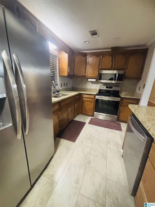 kitchen featuring a textured ceiling, sink, and appliances with stainless steel finishes