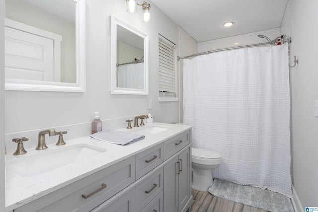 bathroom featuring wood-type flooring, vanity, toilet, and curtained shower