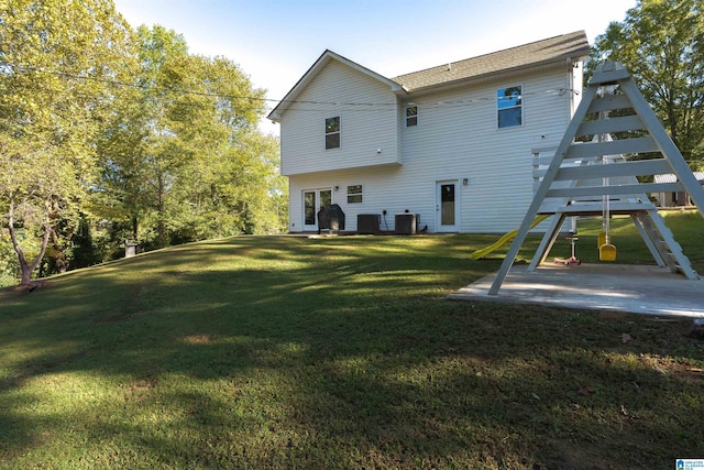 back of house featuring a lawn, a playground, a patio, and central air condition unit