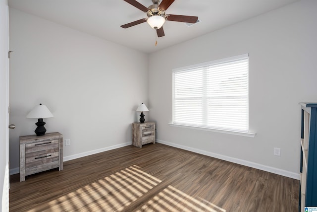 unfurnished bedroom with multiple windows, dark hardwood / wood-style floors, and ceiling fan