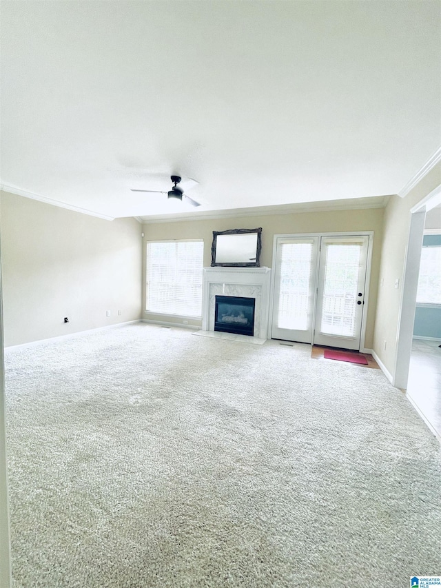 unfurnished living room with carpet, ceiling fan, a premium fireplace, and ornamental molding