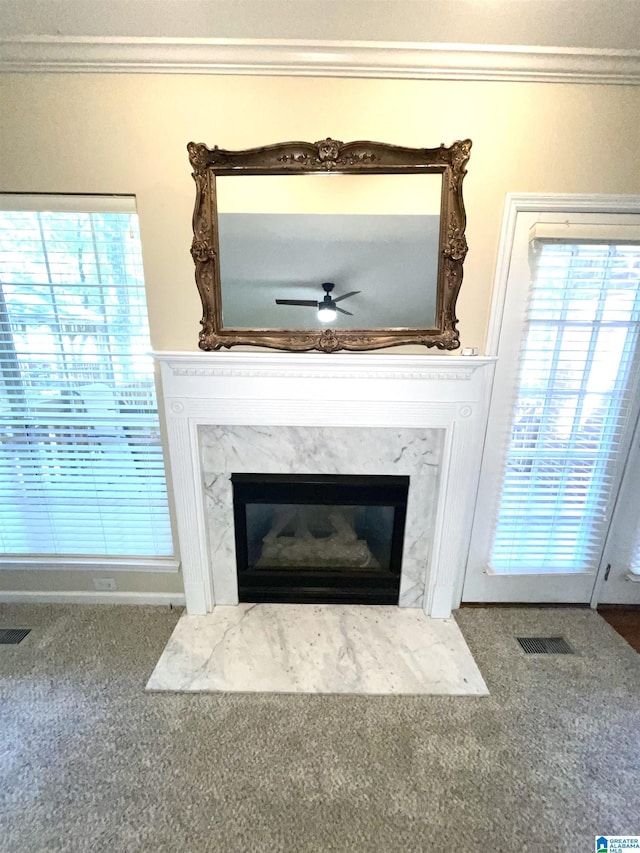 room details featuring carpet flooring, ceiling fan, ornamental molding, and a high end fireplace