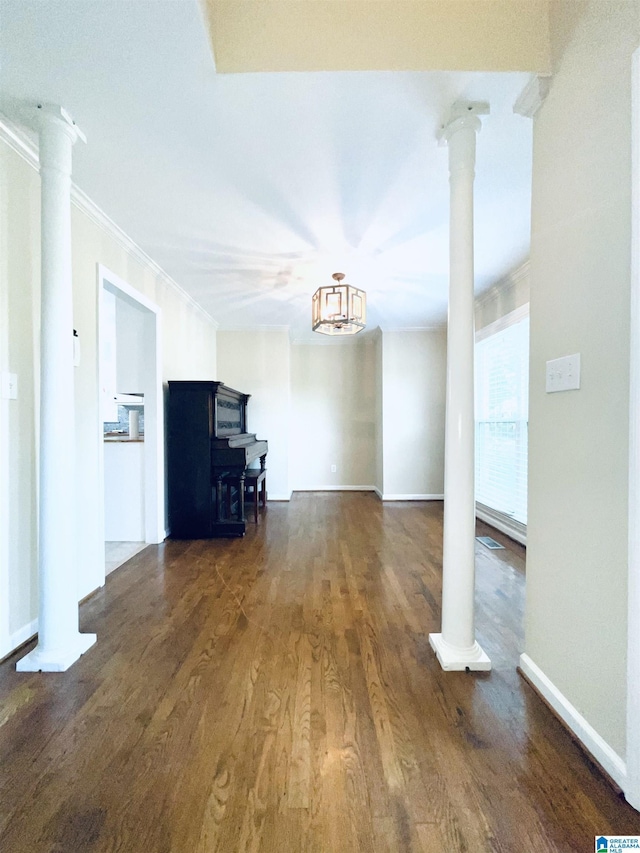 unfurnished living room featuring ornate columns, dark hardwood / wood-style flooring, an inviting chandelier, and ornamental molding