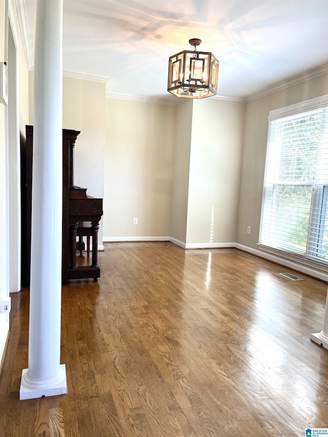 living room featuring hardwood / wood-style floors, a notable chandelier, crown molding, and decorative columns