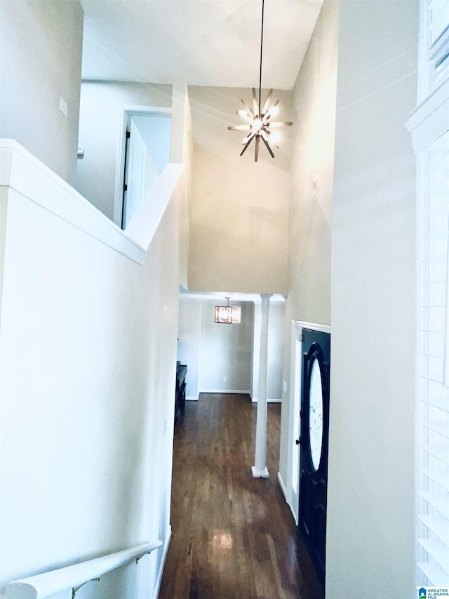 corridor with dark hardwood / wood-style flooring, a high ceiling, and a chandelier