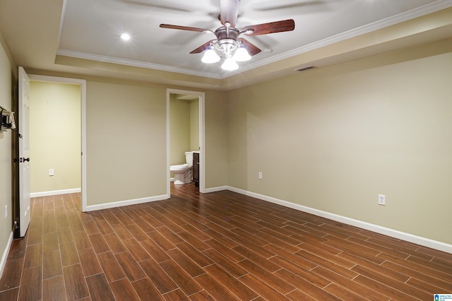 unfurnished bedroom with a tray ceiling, ceiling fan, ensuite bathroom, and ornamental molding