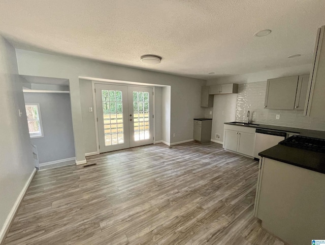 kitchen with backsplash, hardwood / wood-style floors, sink, white dishwasher, and french doors