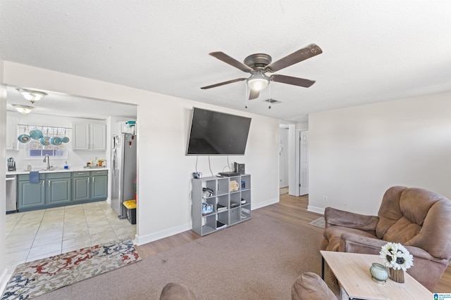 living room featuring ceiling fan, sink, and a textured ceiling