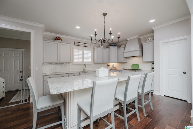 kitchen with decorative light fixtures, a center island, custom range hood, and dark wood-type flooring