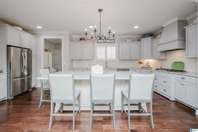 kitchen featuring an inviting chandelier, decorative light fixtures, a kitchen island, custom range hood, and stainless steel appliances