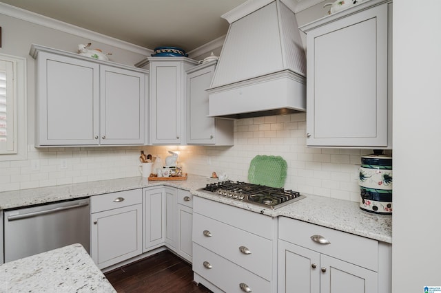 kitchen with backsplash, light stone countertops, custom range hood, and appliances with stainless steel finishes