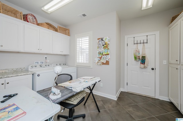 clothes washing area featuring dark tile patterned flooring, washer and dryer, and cabinets