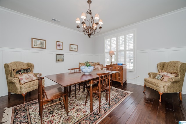 dining space featuring crown molding, dark wood-type flooring, and an inviting chandelier