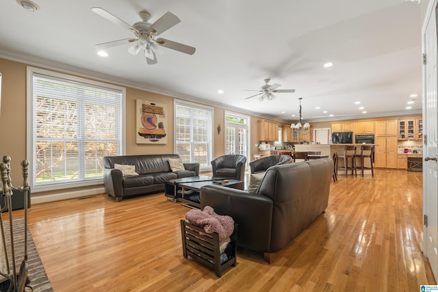 living room with light wood-type flooring, ceiling fan with notable chandelier, and ornamental molding