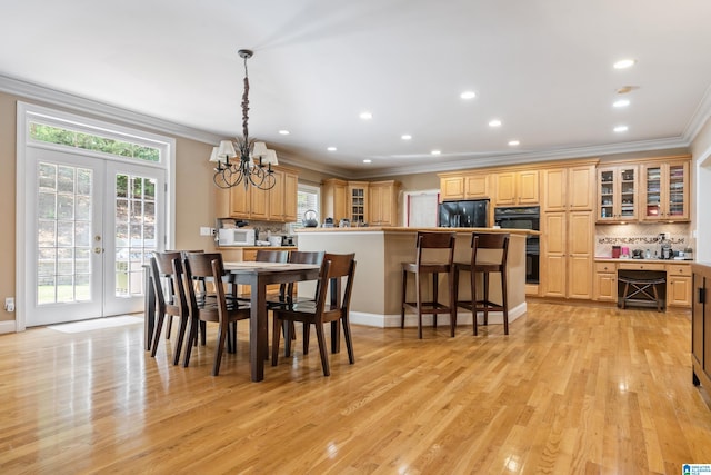 dining space with a chandelier, french doors, crown molding, and light hardwood / wood-style flooring