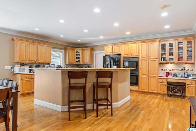 kitchen with a center island, black appliances, and light hardwood / wood-style flooring