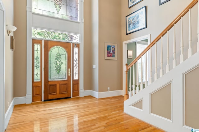 foyer with plenty of natural light, light hardwood / wood-style floors, and a high ceiling