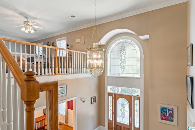 foyer featuring ceiling fan with notable chandelier and crown molding