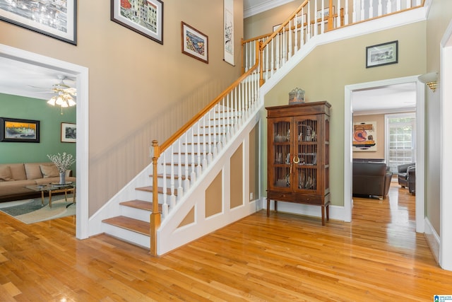 stairs featuring ceiling fan, ornamental molding, and hardwood / wood-style flooring