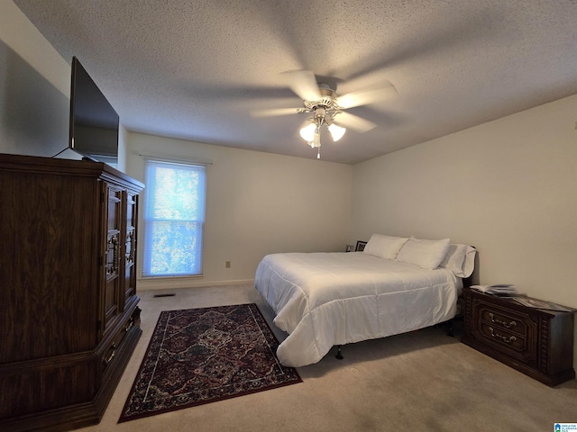 carpeted bedroom featuring ceiling fan and a textured ceiling