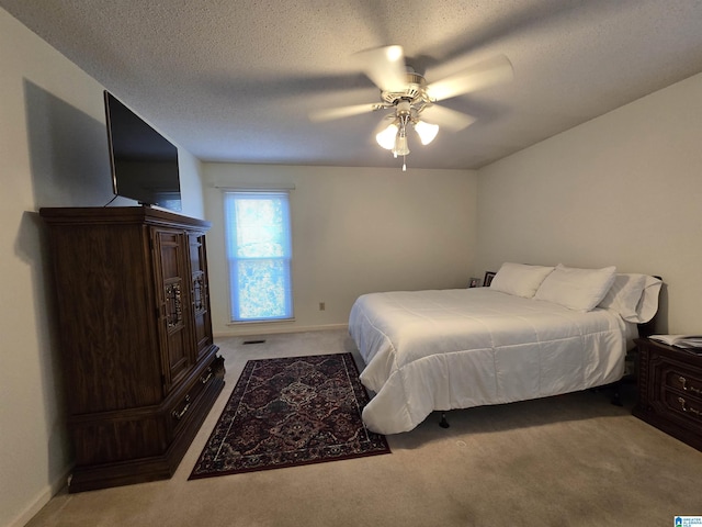 bedroom with ceiling fan, light carpet, and a textured ceiling