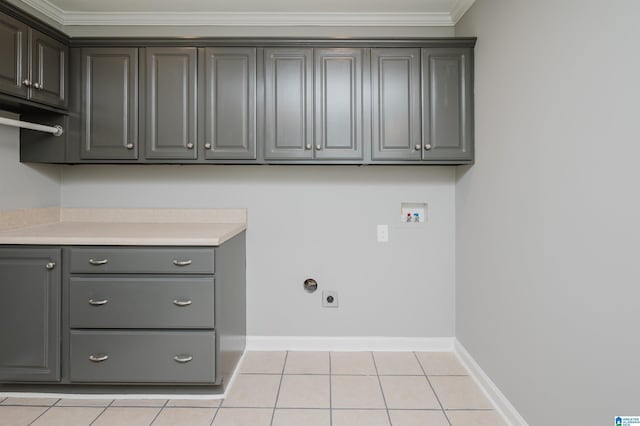 washroom featuring crown molding, hookup for a washing machine, light tile patterned flooring, and cabinets