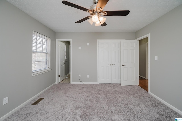 unfurnished bedroom featuring a textured ceiling, ceiling fan, light carpet, and a closet