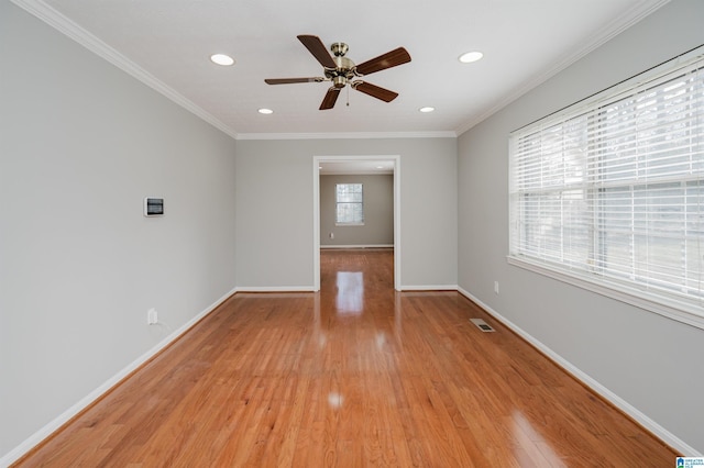 empty room featuring ceiling fan, plenty of natural light, crown molding, and light wood-type flooring