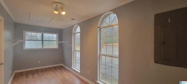 doorway featuring electric panel, light hardwood / wood-style flooring, a textured ceiling, and ornamental molding