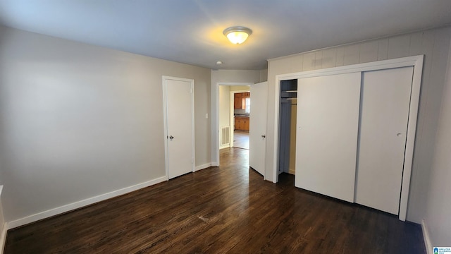 unfurnished bedroom with dark hardwood / wood-style flooring and a closet