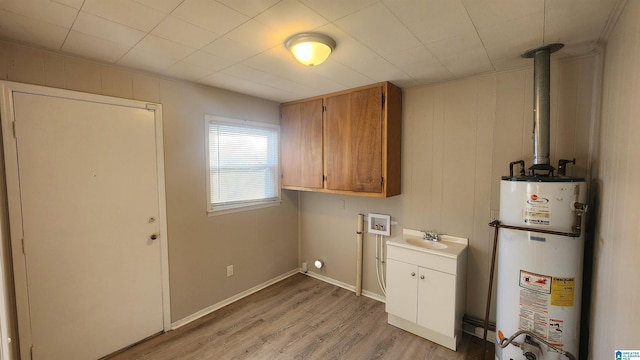 laundry area featuring cabinets, hookup for a washing machine, gas water heater, sink, and light hardwood / wood-style floors