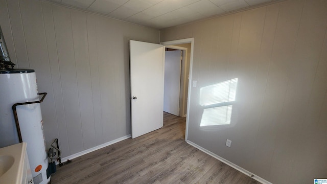 interior space featuring wood walls, gas water heater, and light wood-type flooring